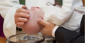 Bilde av et barn som blir døpt ved døpefonten i en kirke av en prest