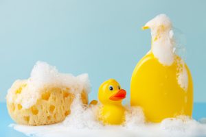 Baby shampoo on a white background, rubber yellow ducks, soap foam. Bathroom accessories