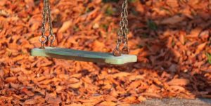 Foto av en svinghuske om høsten med mange blader på bakken