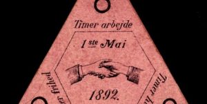 En trekant på svart bakgrunn med tekst "attetimersdag" fra 1892.