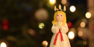 Bilde av en poselensfigur av Lucia med hvit kjole og lyskrans på hodet